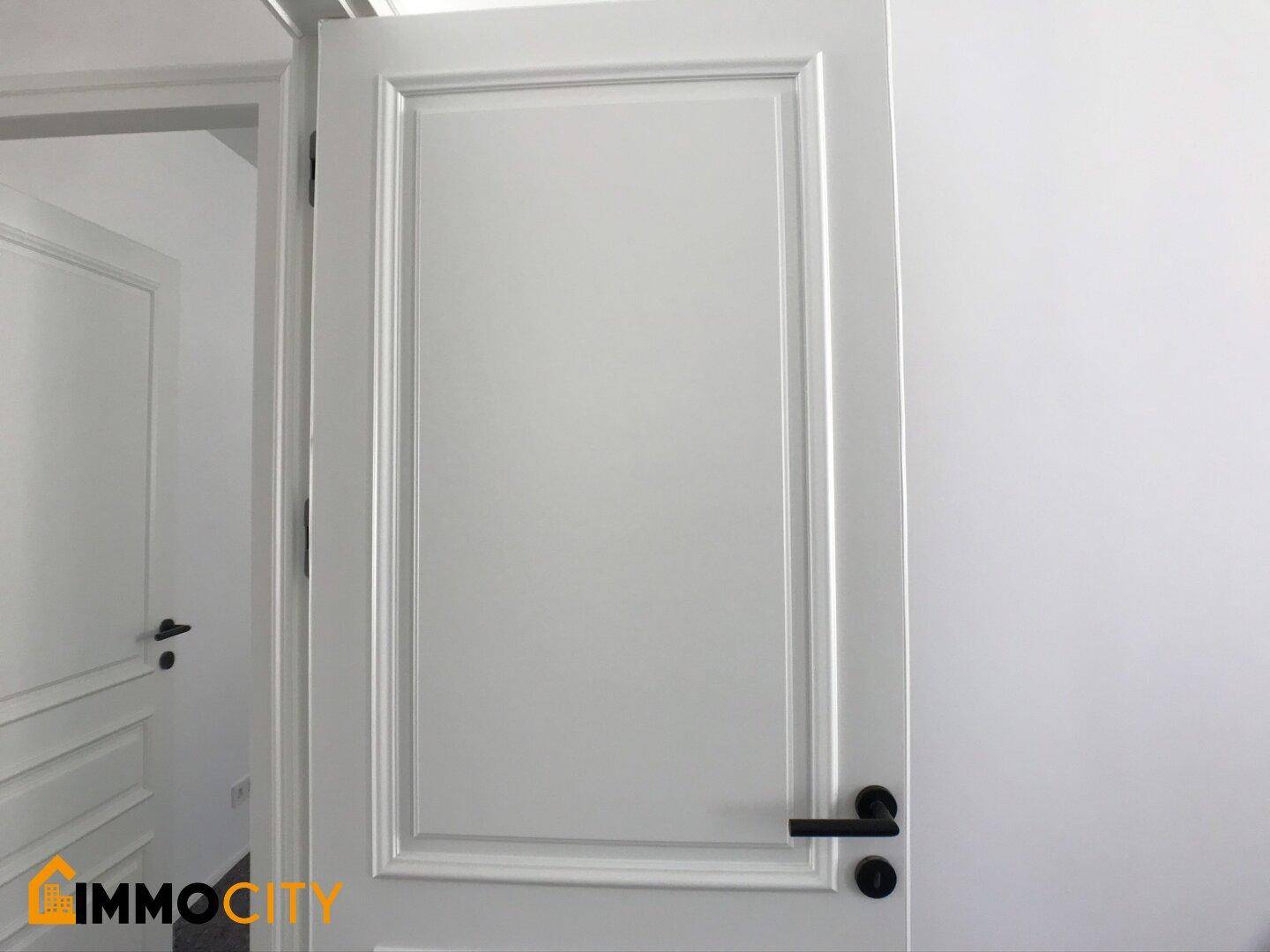 Detailaufnahme einer modernen weißen Innentür mit stilvollem schwarzem Türgriff.