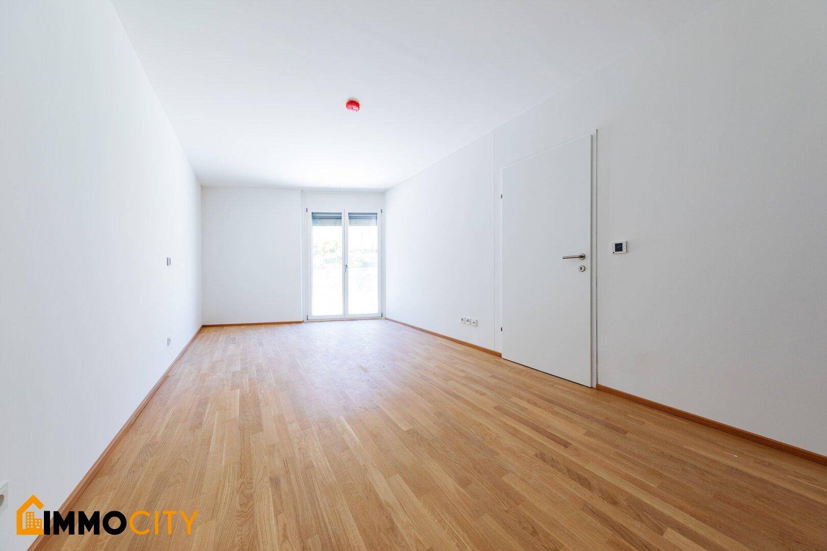 Geräumiges Schlafzimmer mit Parkettboden und Fenster mit Rollläden für angenehme Ruhe.