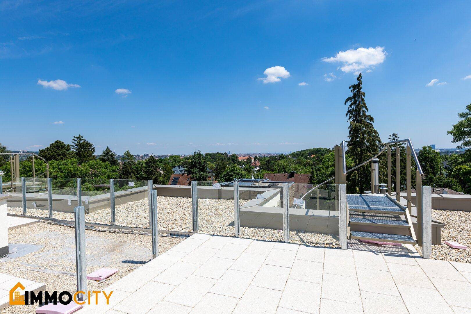 Geräumige Dachterrasse mit Fliesenboden und Glasgeländer bietet weite Aussicht.