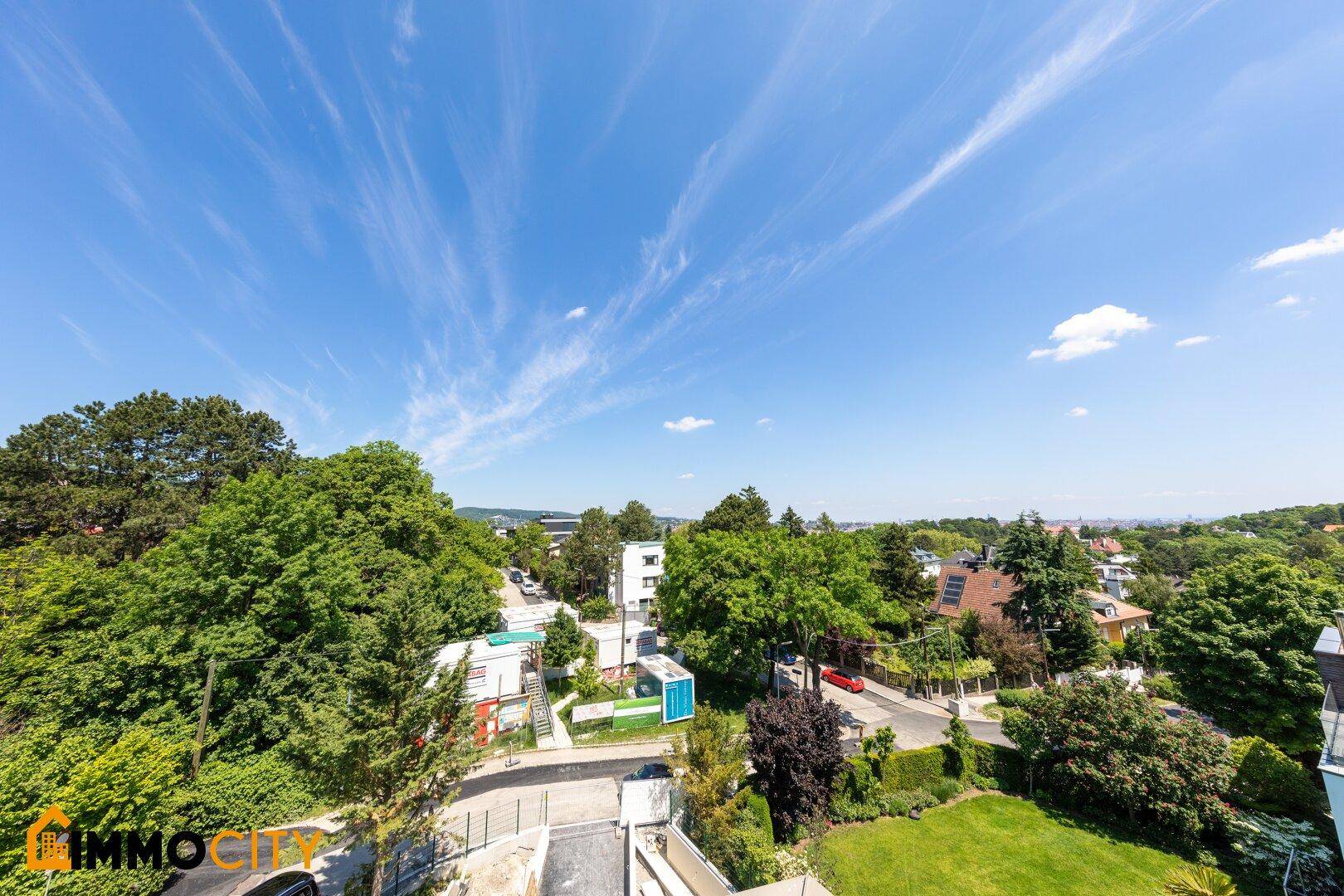 Weitläufiger Panoramablick über die grüne Umgebung und die Stadt unter blauem Himmel.