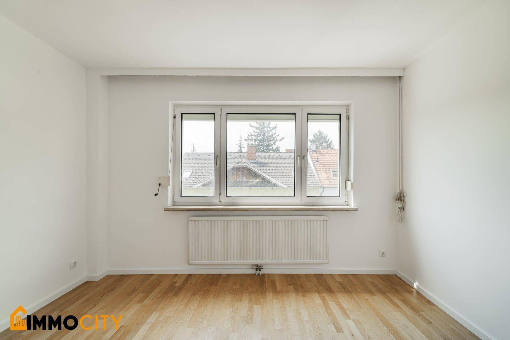 Gemütliches Schlafzimmer mit hellem Parkettboden und einem Fenster, das den Raum gut belichtet.