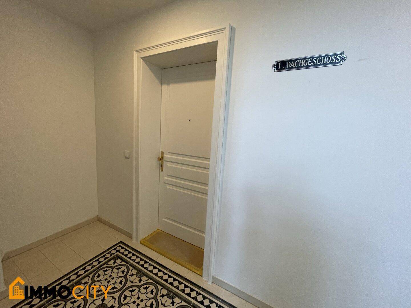 Eingangsbereich einer Wohnung im ersten Dachgeschoss mit gemusterten Fliesen und weißer Tür.