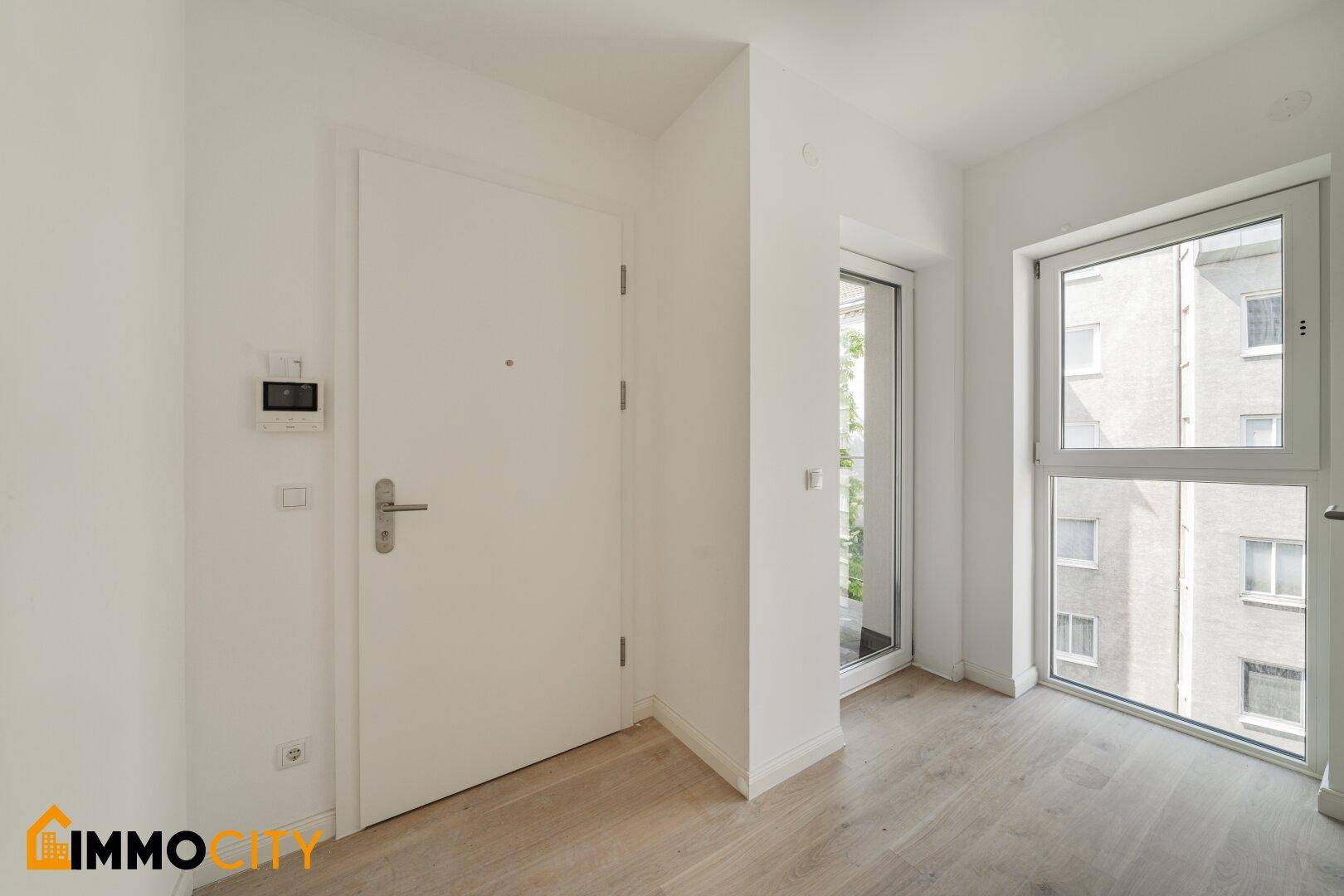 Eingangsbereich mit heller Holzboden und einer modernen Wohnungstür.