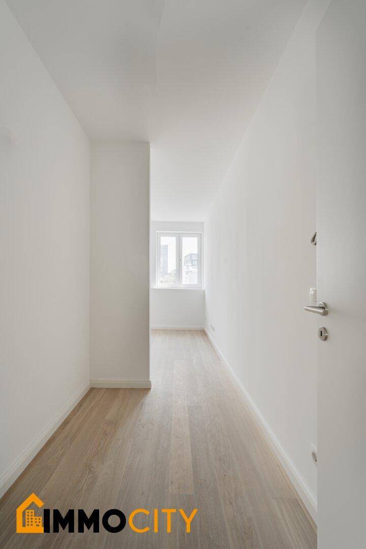Helles Schlafzimmer mit Holzboden und einem Fenster am Ende des Raumes.