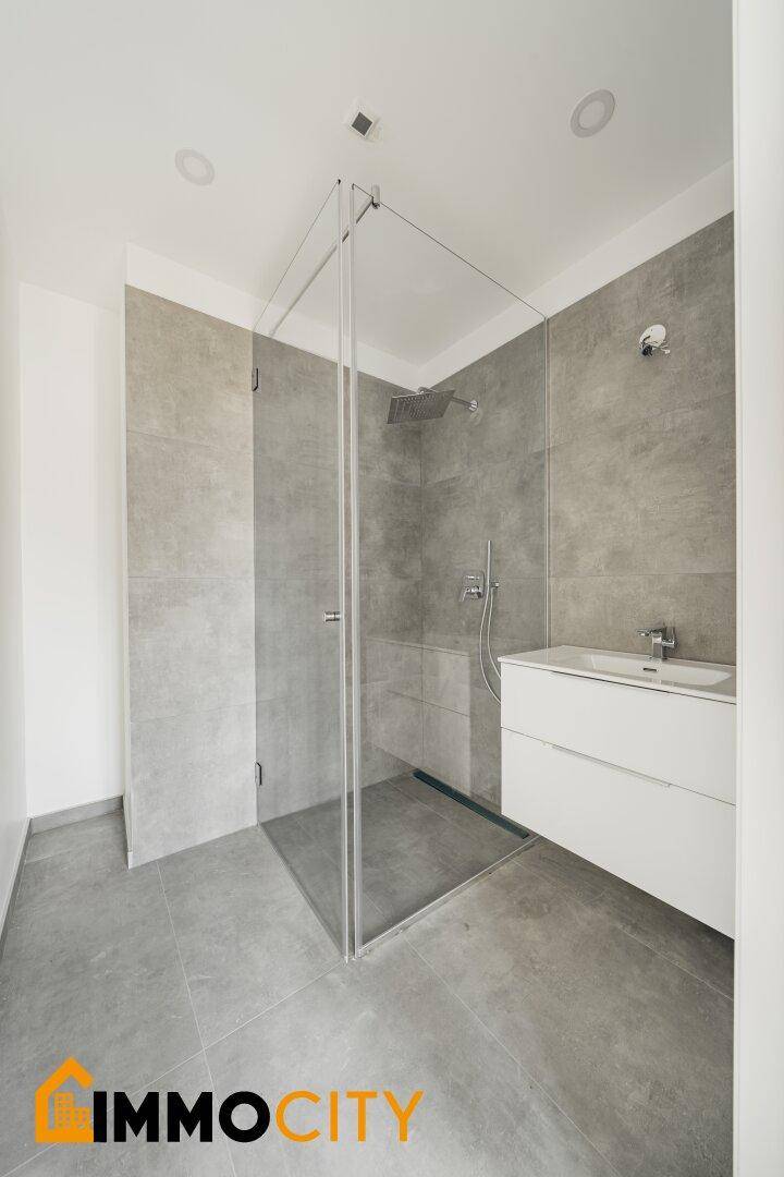 Elegantes Badezimmer mit geräumiger Glasdusche und modernem Waschtisch.