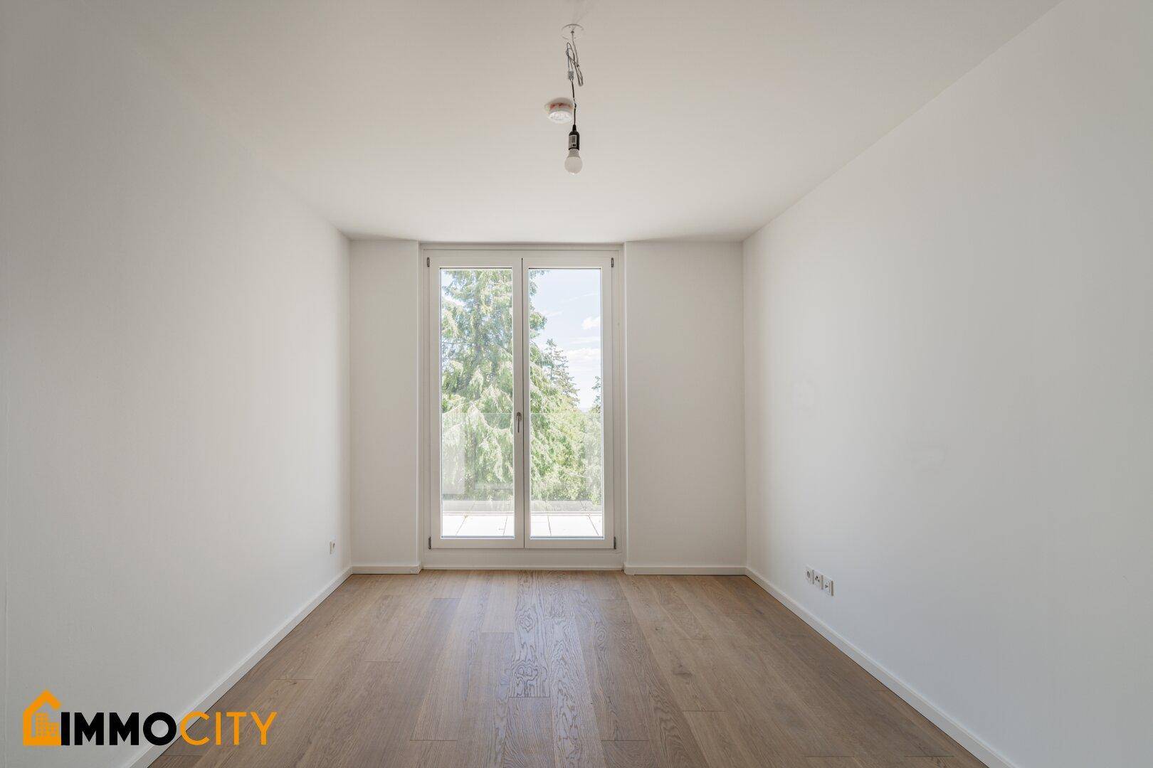 Helles Schlafzimmer mit Zugang zum Balkon und schönem Ausblick ins Grüne.