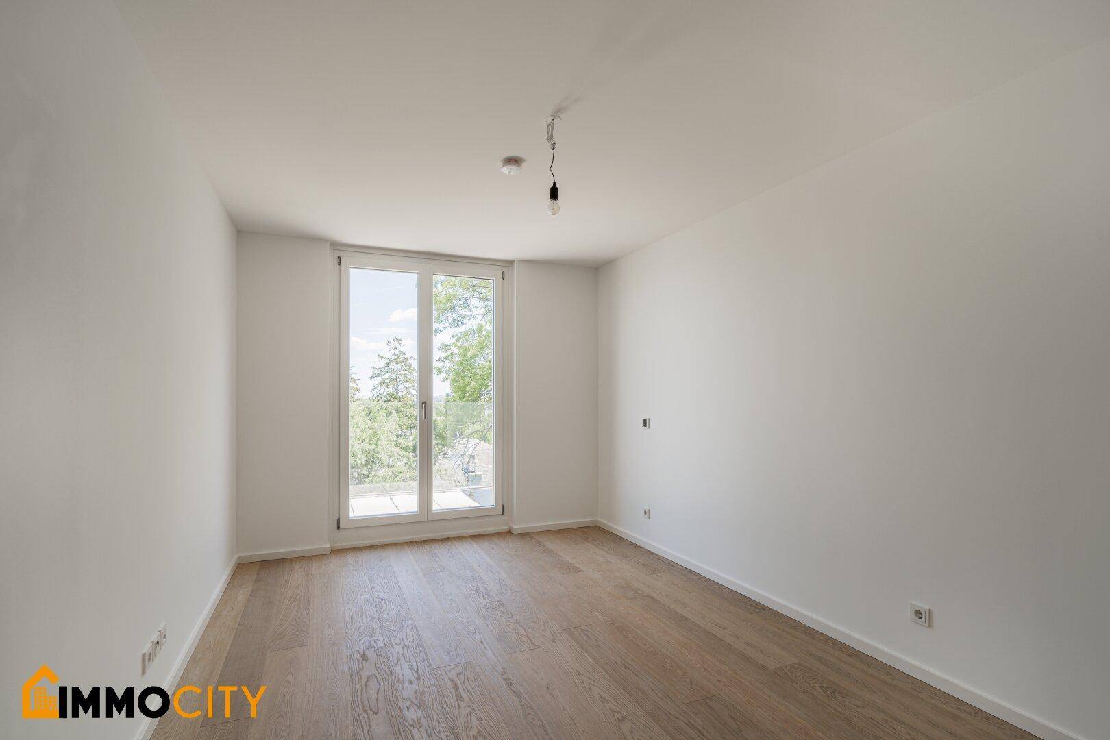 Helles Schlafzimmer mit großen Fenstern und Blick ins Grüne.