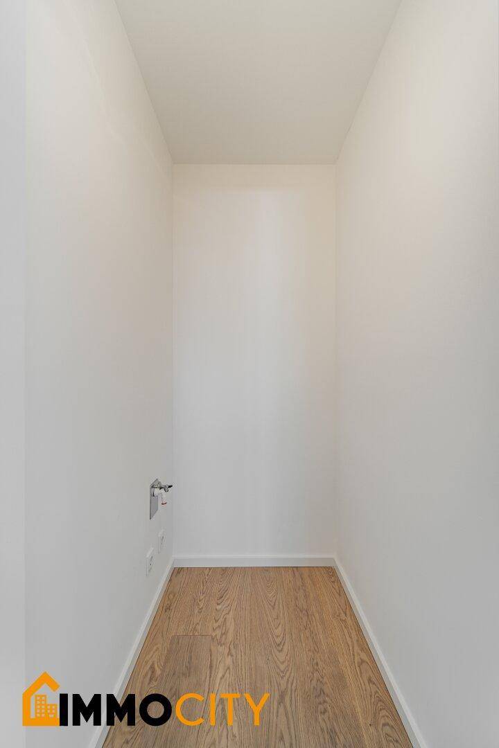 Kleiner Abstellraum mit hellen Wänden und Holzfußboden, ideal für Waschmaschine oder Lagerung.