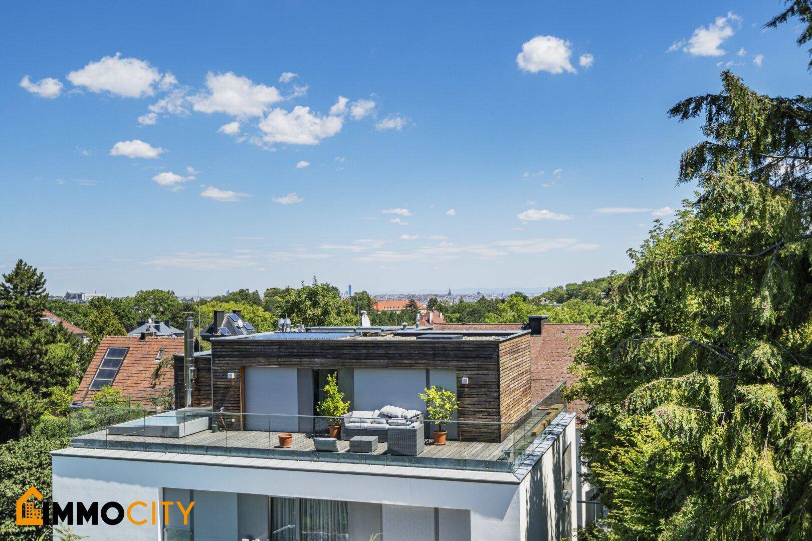Dachterrassenbereich eines modernen Gebäudes mit Sitzgelegenheiten und weitem Blick über die Stadt.