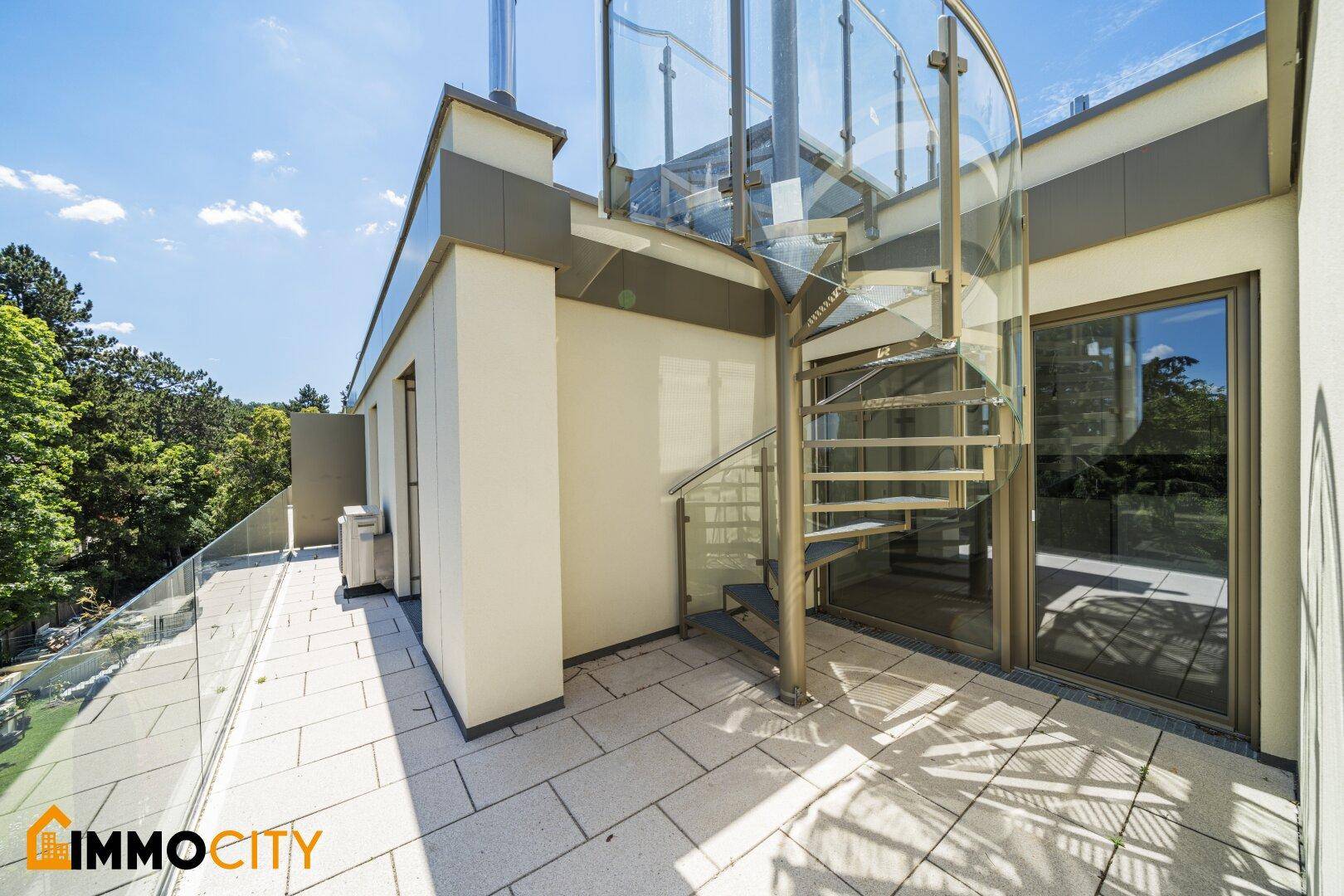 Geräumige Dachterrasse mit moderner Wendeltreppe aus Glas und Metall sowie Fliesenboden.