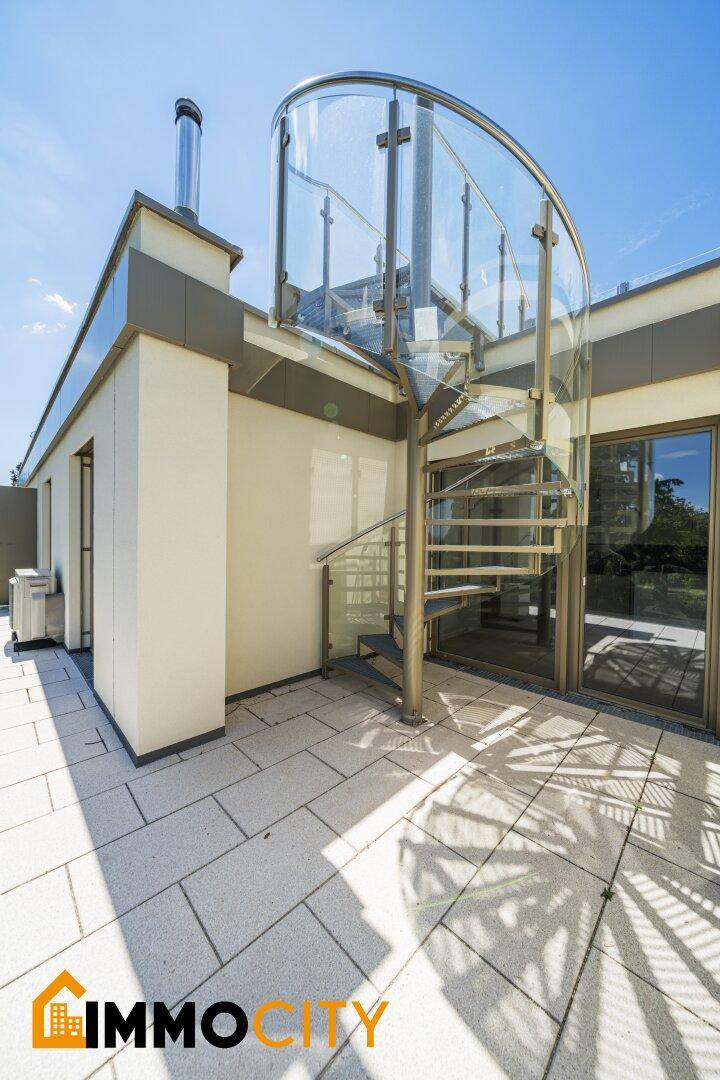 Sonnige Dachterrasse mit eleganter Wendeltreppe und großzügiger Fläche für Entspannung im Freien.