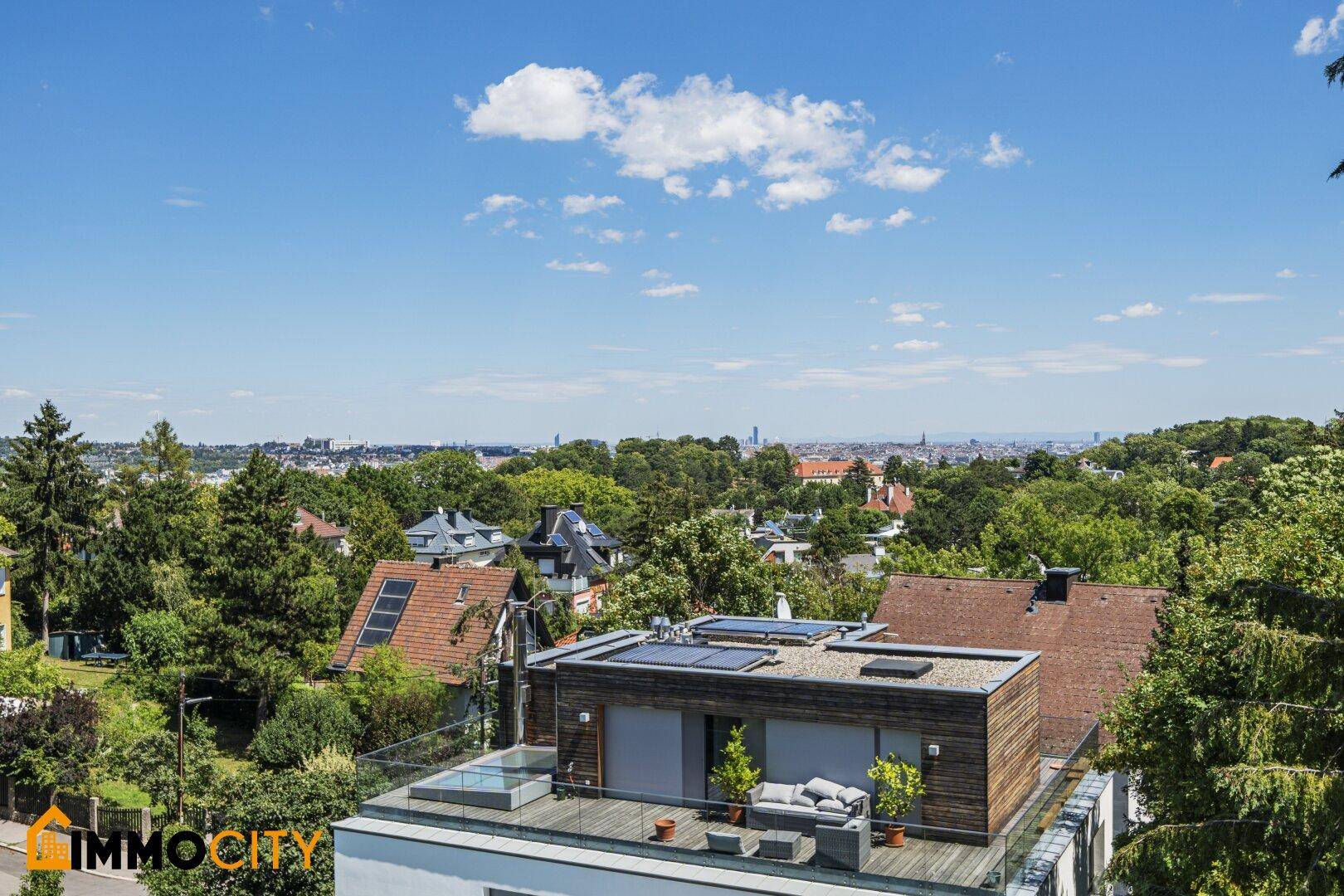Dachterrassenbereich mit Whirlpool und Sitzgelegenheiten, umgeben von Bäumen und Stadtblick.