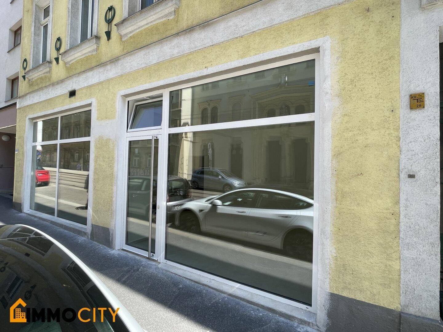 Nahaufnahme der gelben historischen Fassade mit großen Schaufenstern im Erdgeschoss.