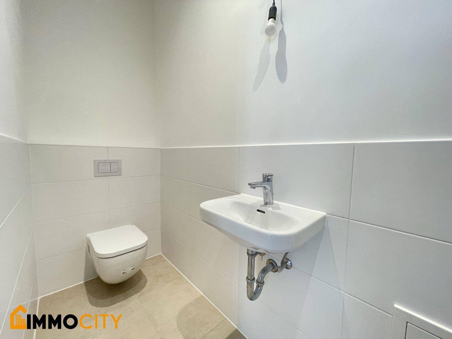Modernes Gäste-WC mit wandhängender Toilette und kleinem Waschbecken in minimalistischem Design.