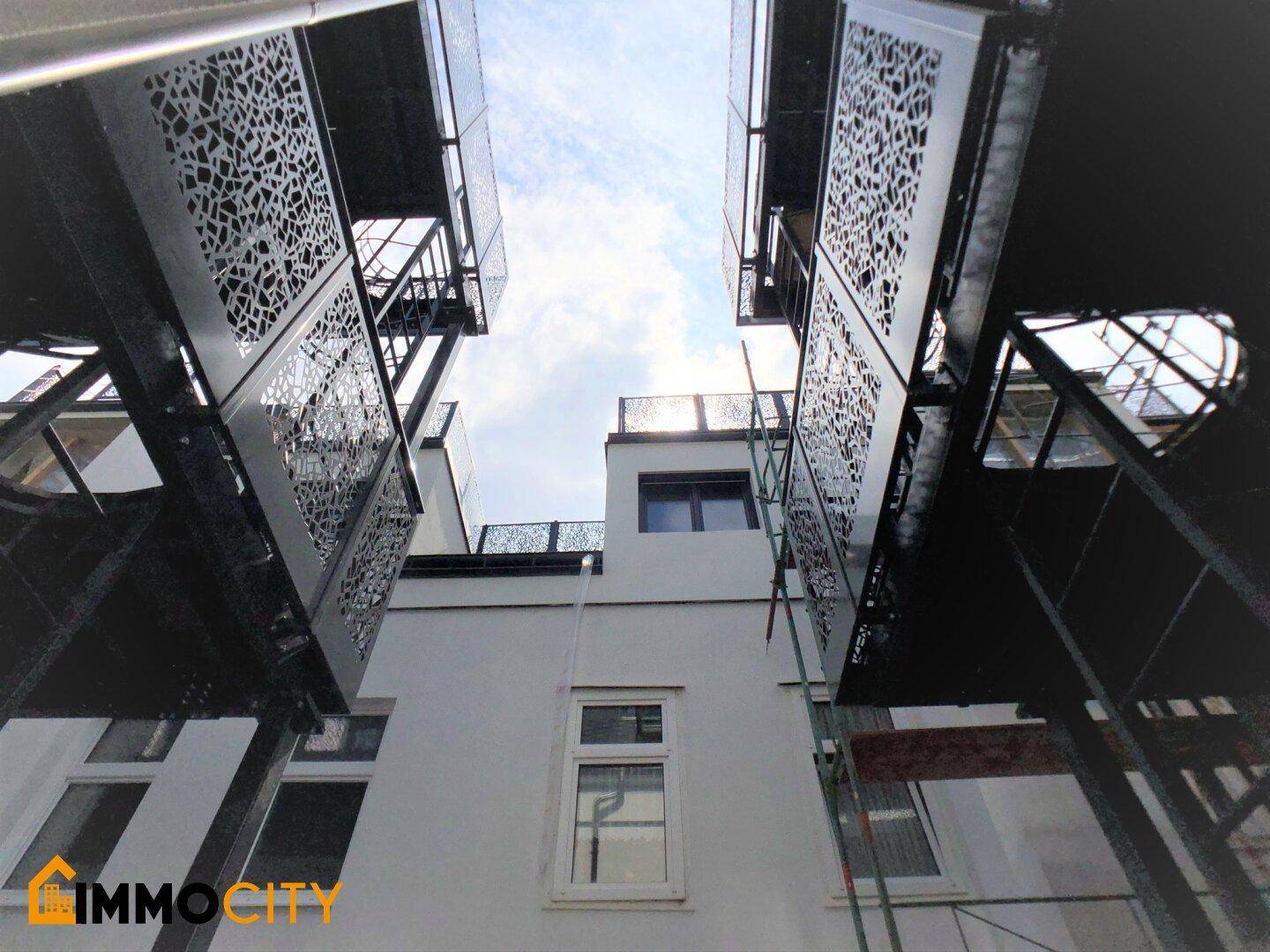 Moderne Gebäudefassade mit kunstvoll gestalteten Metallbalkonen und klarem Himmel.