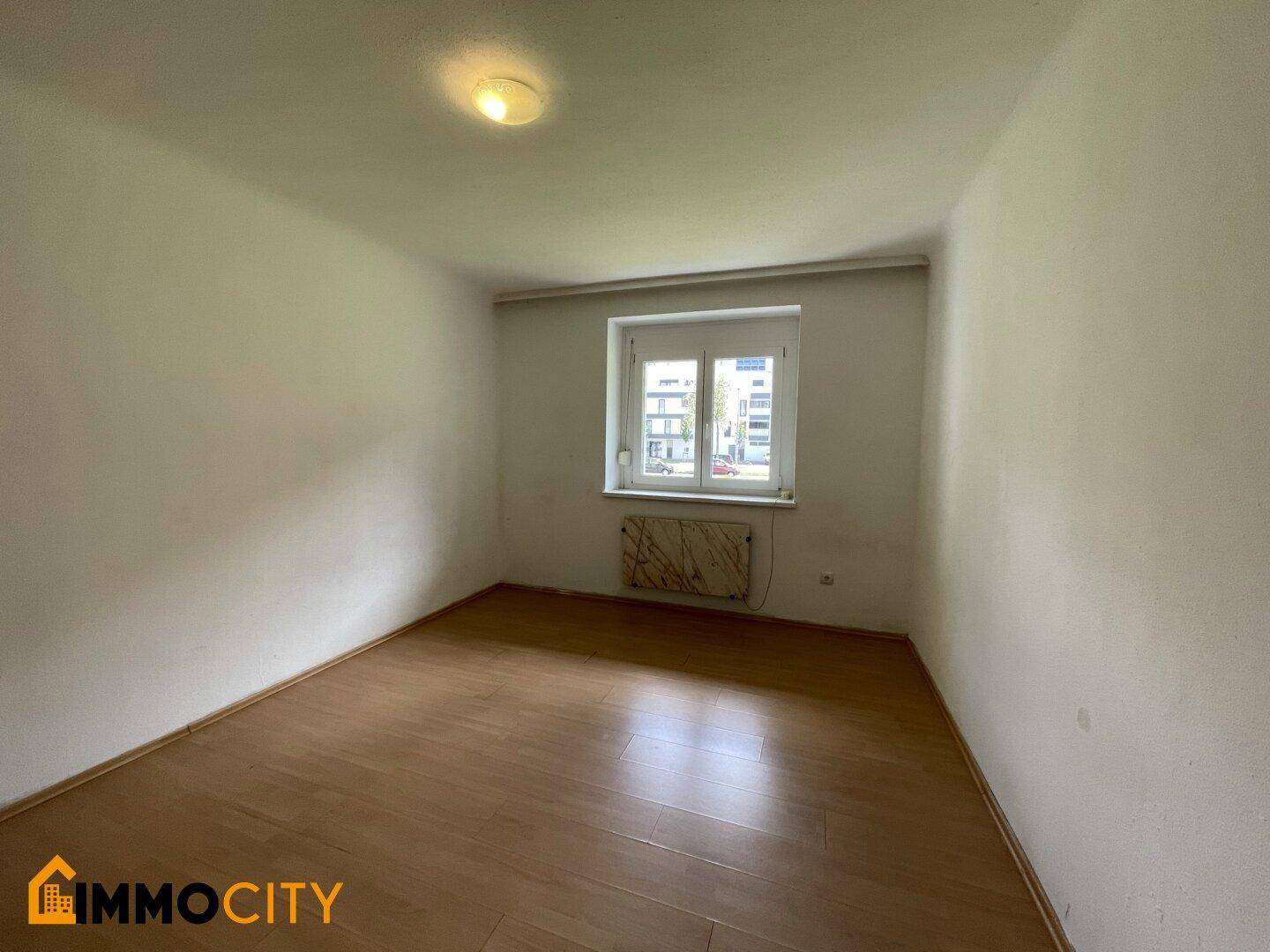Ruhiges Schlafzimmer mit Laminatboden und Fenster, ideal für erholsame Nächte.