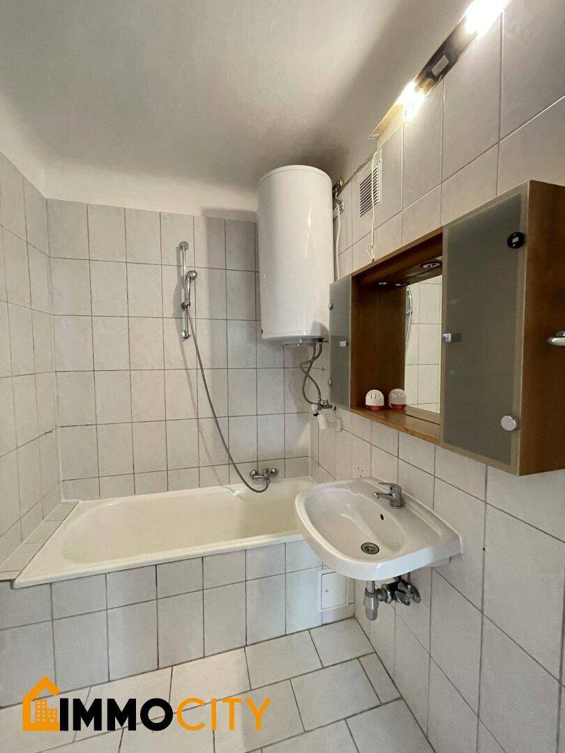 Gefliestes Badezimmer mit Badewanne, Waschbecken und Spiegelschrank.