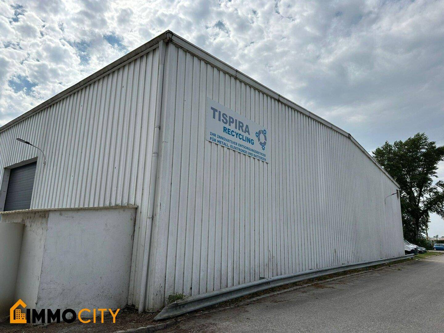 Seitenansicht des Industriegebäudes mit Wellblechfassade und einem Firmenlogo für Recycling.