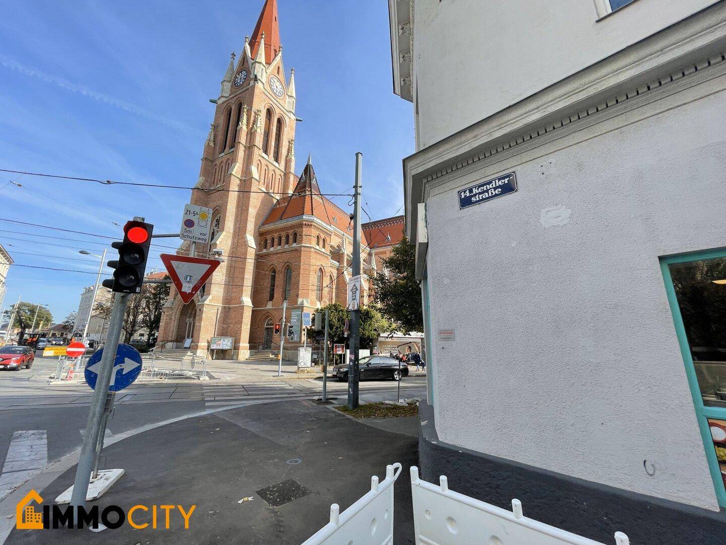 Straßenansicht mit einer imposanten Kirche im Hintergrund und einer belebten Kreuzung mit Ampeln.