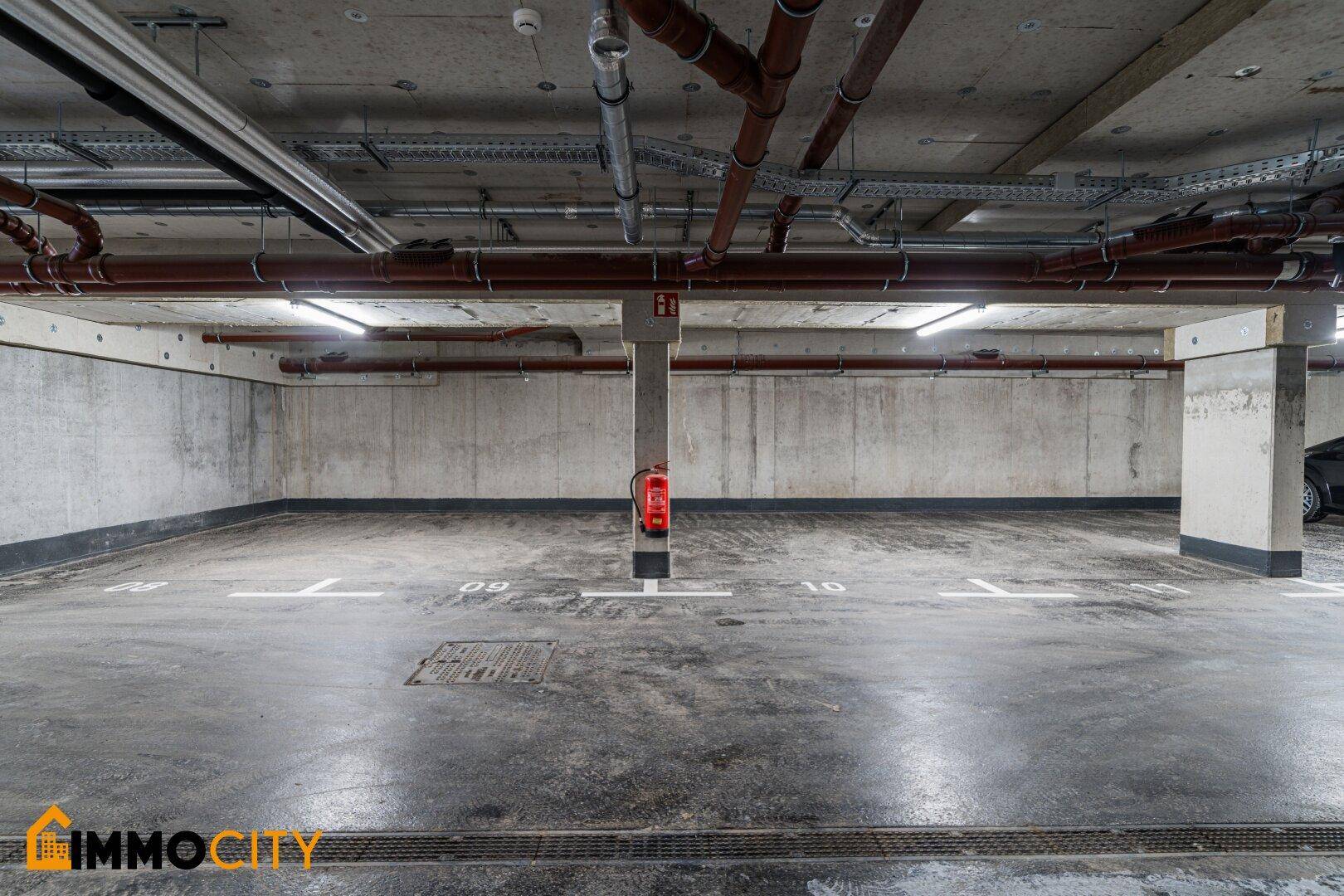 Geräumige Tiefgarage mit Betonboden und markierten Parkplätzen.