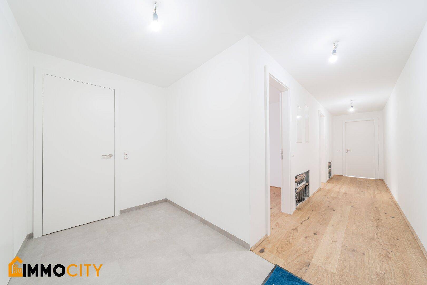 Heller Flur mit Holzboden und Zugang zu verschiedenen Zimmern im Neubau.