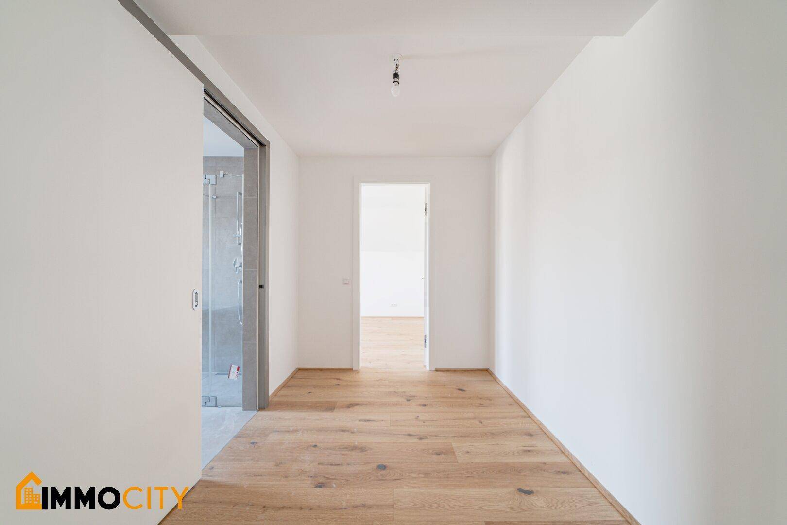 Heller Flur mit Holzboden und Zugang zu weiteren Räumen und einem Badezimmer.
