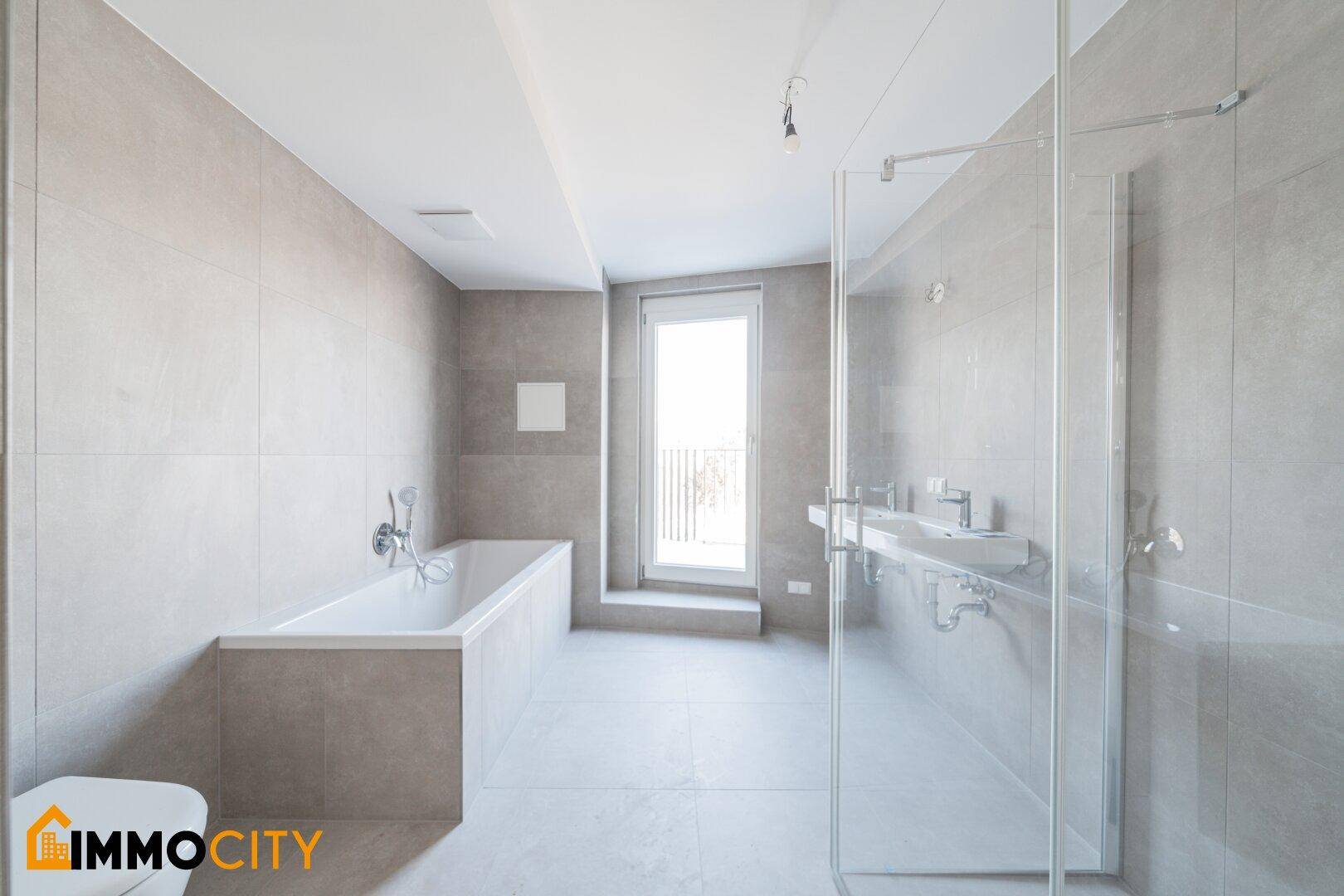 Geräumiges Badezimmer mit Badewanne, Dusche und Fenster für natürliches Licht.