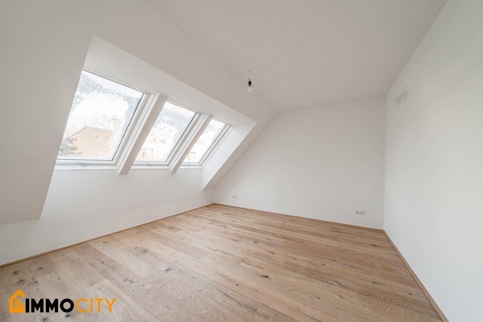Helles Zimmer im Dachgeschoss mit Holzboden und drei Dachfenstern, ideal als Schlafzimmer.