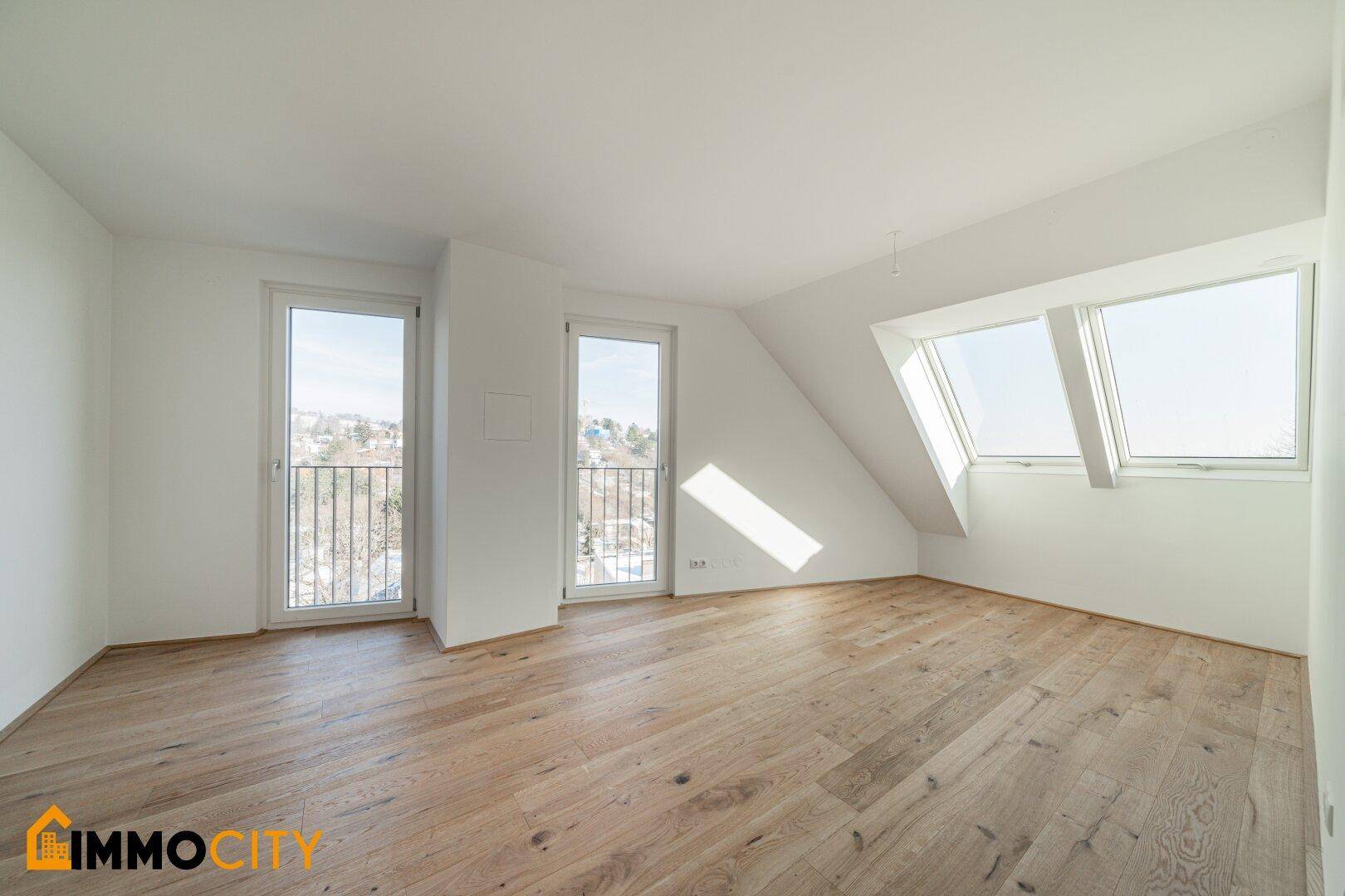 Geräumiges Zimmer mit Holzboden, französischen Balkonen und Dachfenstern, das viel Licht bietet.