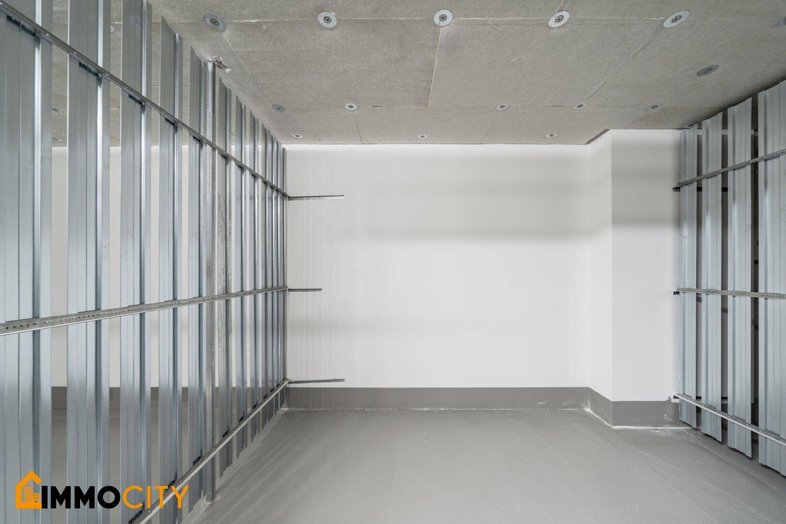 Kellerabteil im Rohbau mit Metallständern und Betonboden, bereit für die Fertigstellung.