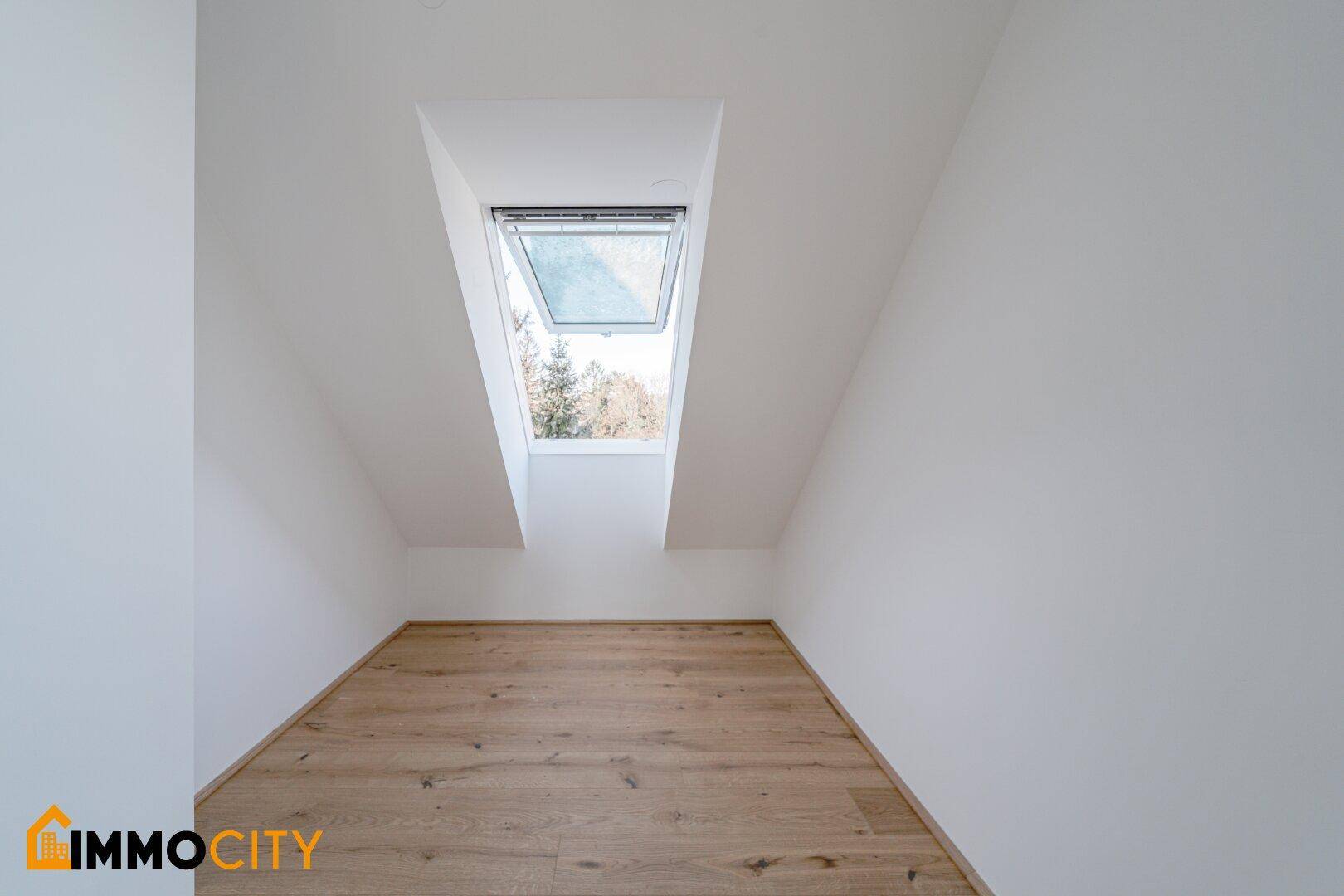 Dachzimmer mit Holzboden und einem großen Dachfenster für viel Tageslicht.