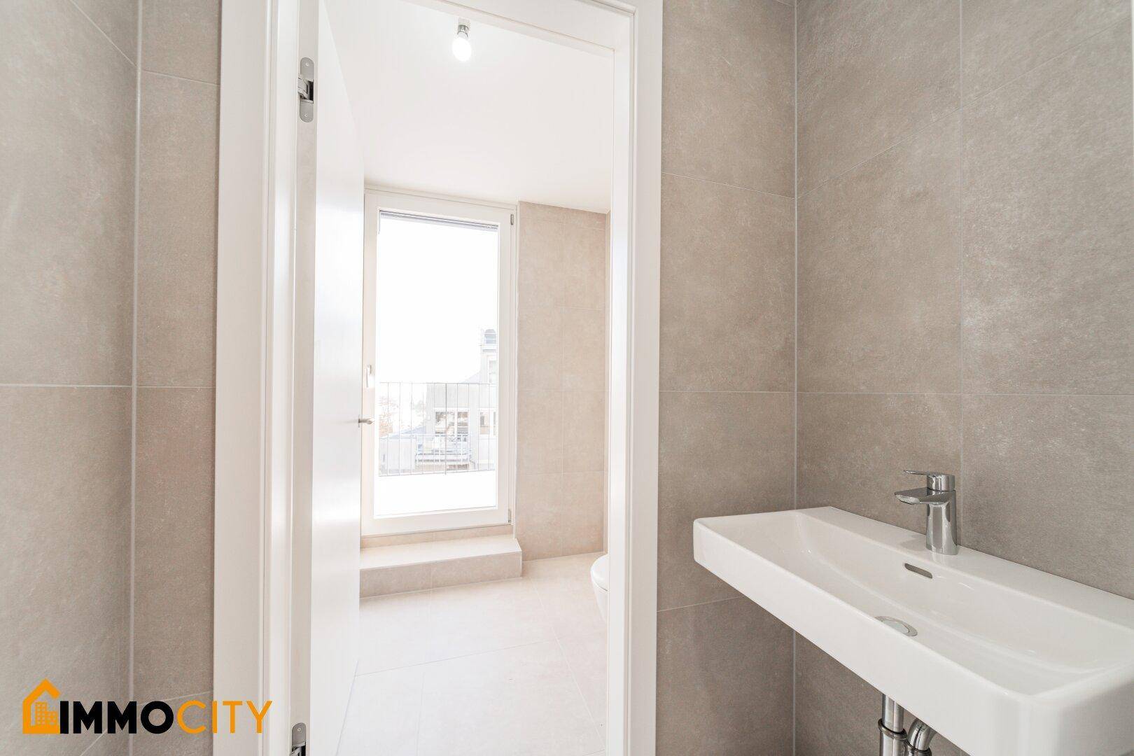 Kleines Badezimmer mit Waschbecken und Zugang zu einem Balkon.