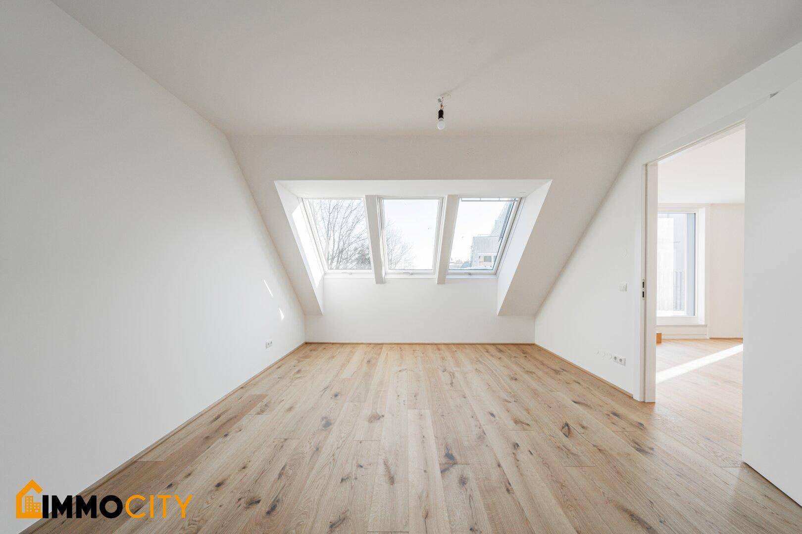 Geräumiger, heller Raum mit Holzboden und Dachfenstern, ideal als Wohn- oder Schlafzimmer.