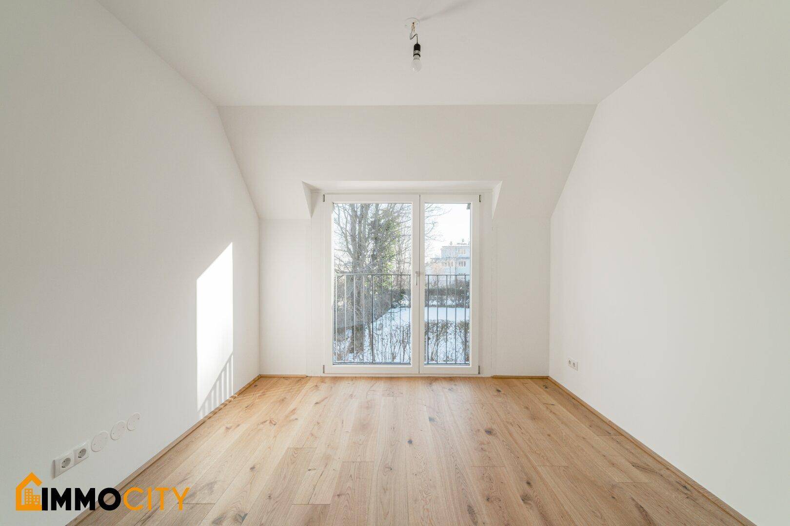 Gemütliches Schlafzimmer mit Holzboden und französischem Balkon, bietet eine helle Atmosphäre.