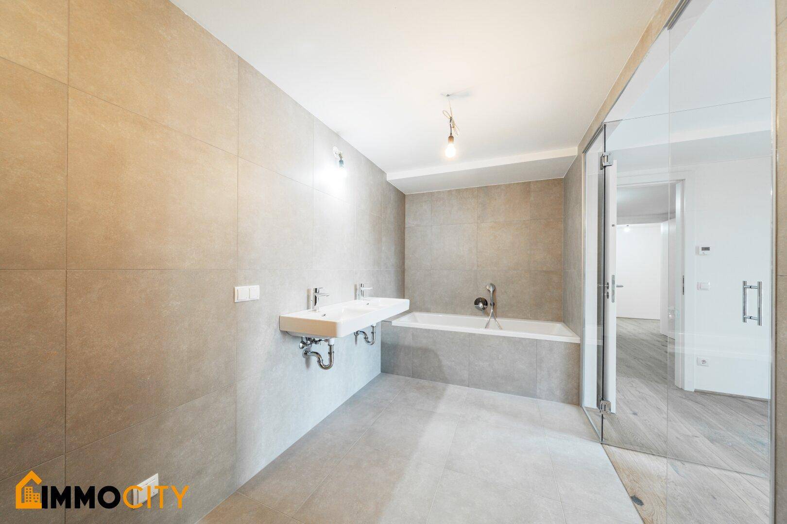 Modernes Badezimmer mit Doppelwaschbecken, Badewanne und Dusche, in hellen Grautönen.