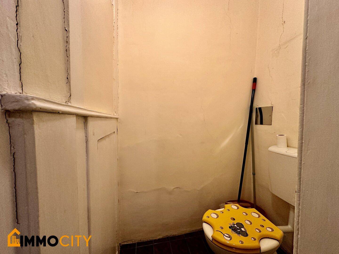 Kleines WC mit einfacher Toilette und Waschbecken, in einem funktionalen Zustand.