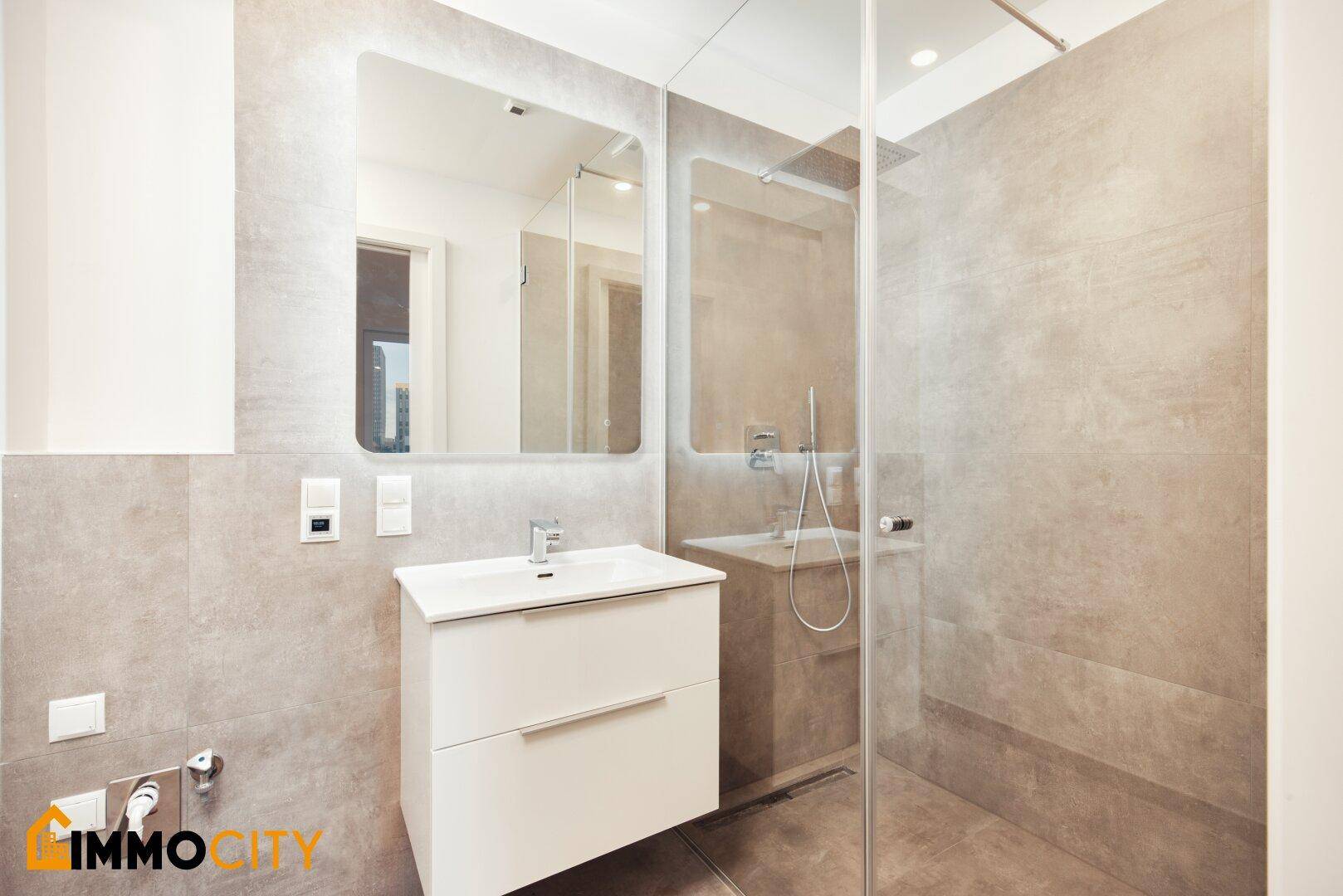 Modernes Badezimmer mit begehbarer Dusche, elegantem Waschtisch und großem beleuchteten Spiegel.