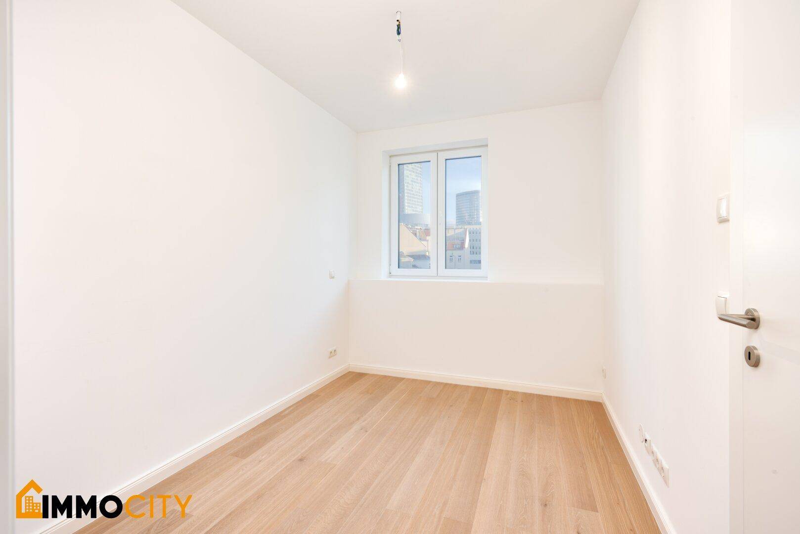 Ruhiges Zimmer mit hellem Holzboden und weiß gestrichenen Wänden, ideal als Schlafzimmer.