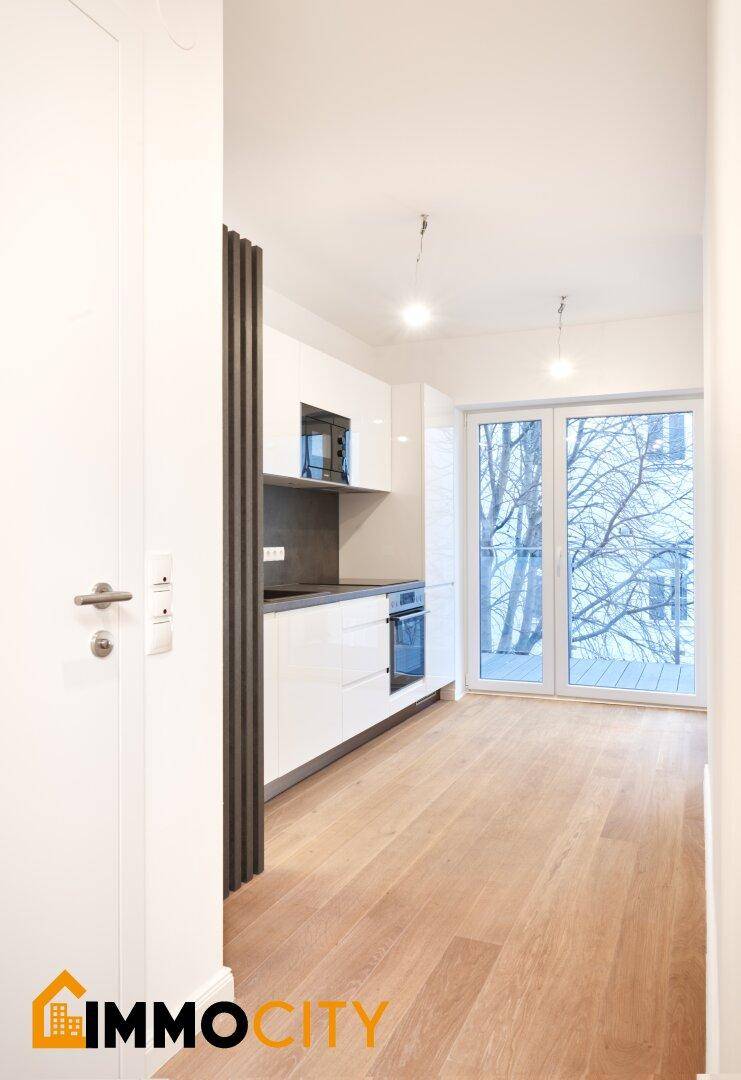 Heller Küchenbereich mit modernen Einbauschränken und Zugang zu einem Balkon.