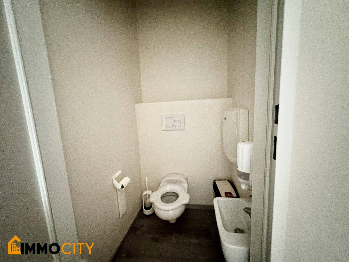 Kleine Toilette mit WC und Waschbecken, einfach und funktional ausgestattet.