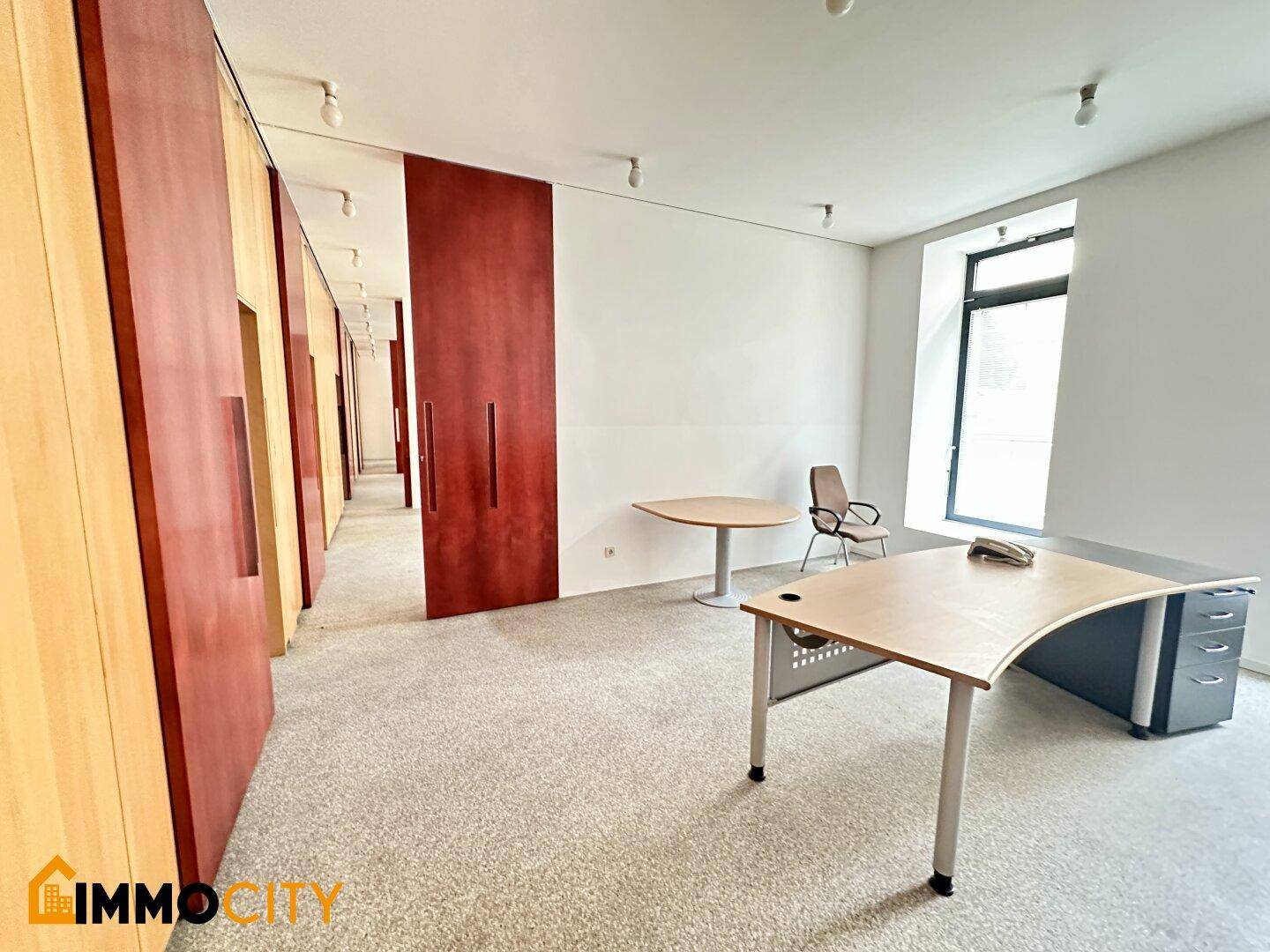 Büro mit Teppichboden, modernen Schreibtischen und einer Reihe von Holzschiebetüren.