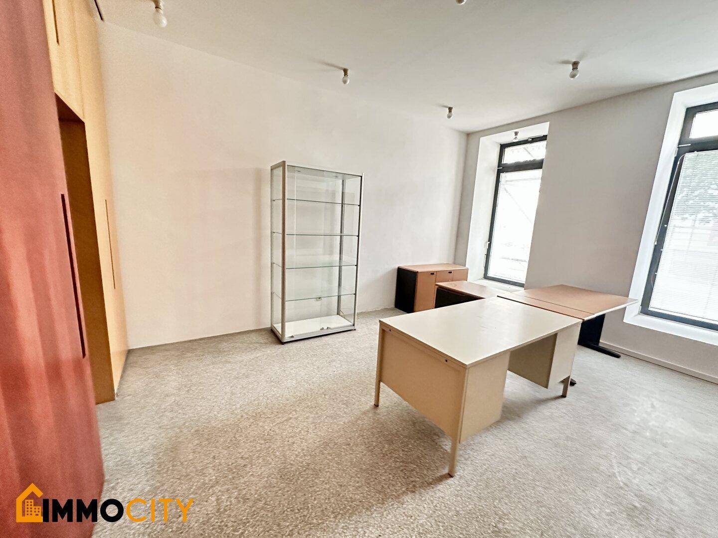 Büro mit Terrazzoboden, modernen Schreibtischen und einer Glasvitrine.