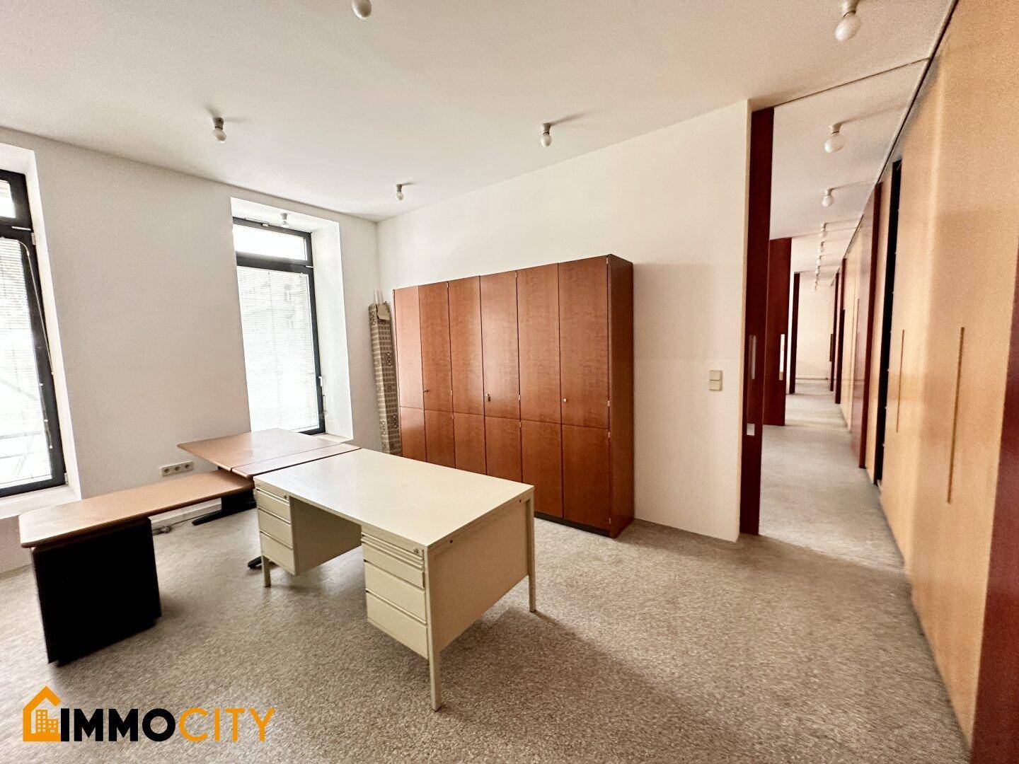 Büro mit Terrazzoboden, Schreibtischen und einer langen Reihe von Holzschränken.