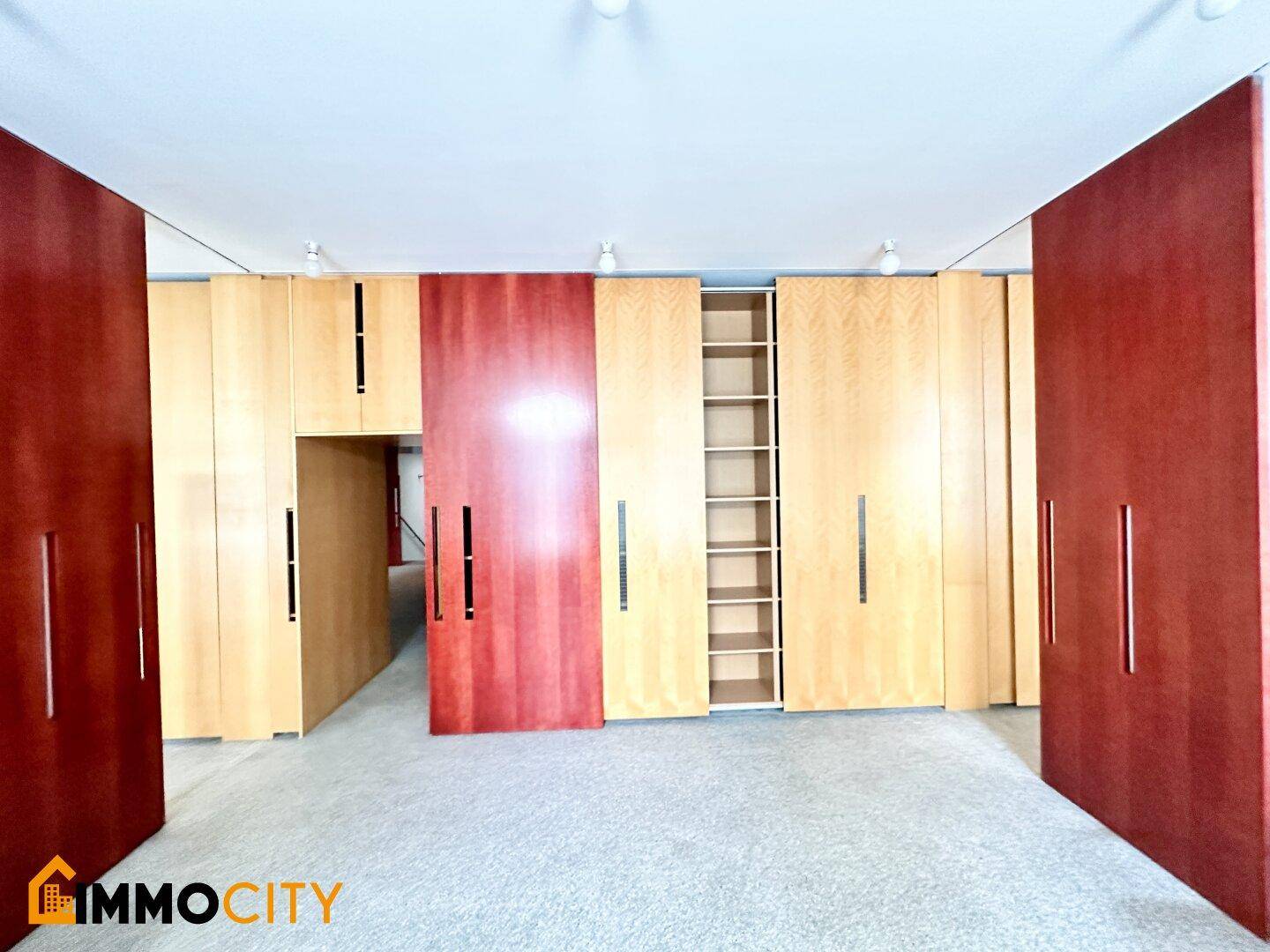 Raum mit modularen Holzschränken in hellen und dunklen Tönen, Teppichboden und indirekter Beleuchtung.