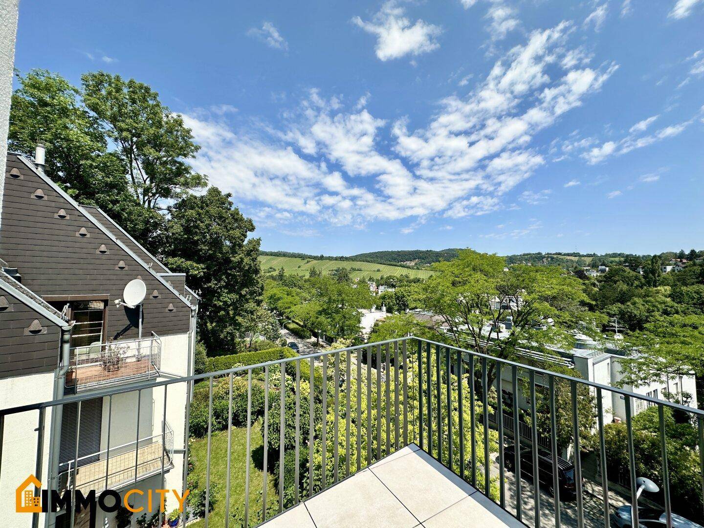 Geräumige Terrasse mit Fliesenboden und weitem Blick über grüne Hügel und die Umgebung.