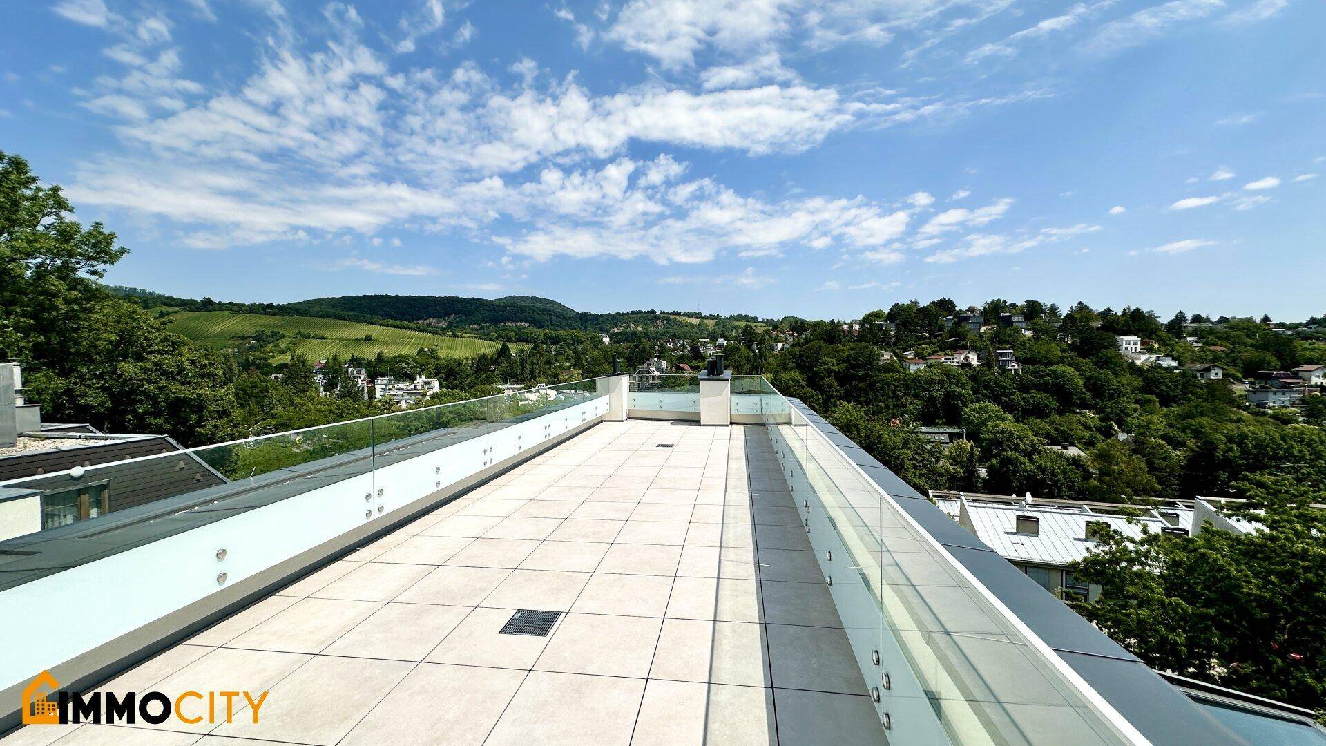Geräumige Dachterrasse mit modernen Glasgeländern und weitem Blick über die grüne Landschaft.