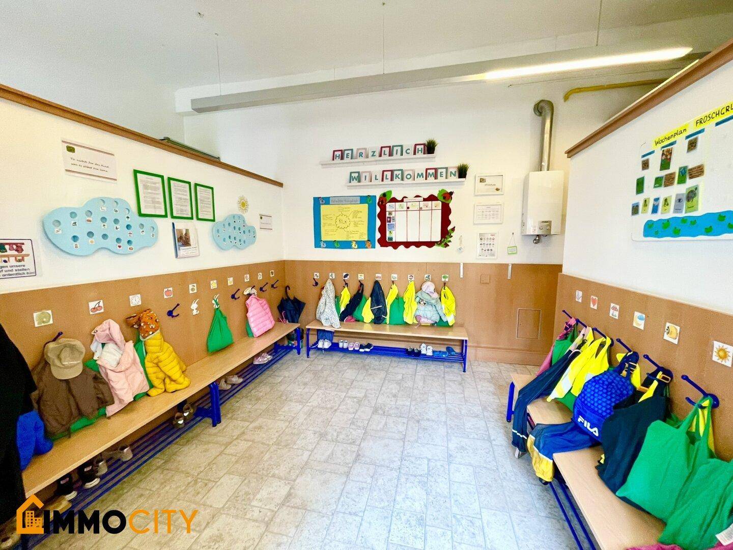 Eingangsbereich mit Garderobe, Bänken und vielen Haken für Kinderkleidung und Schuhe.