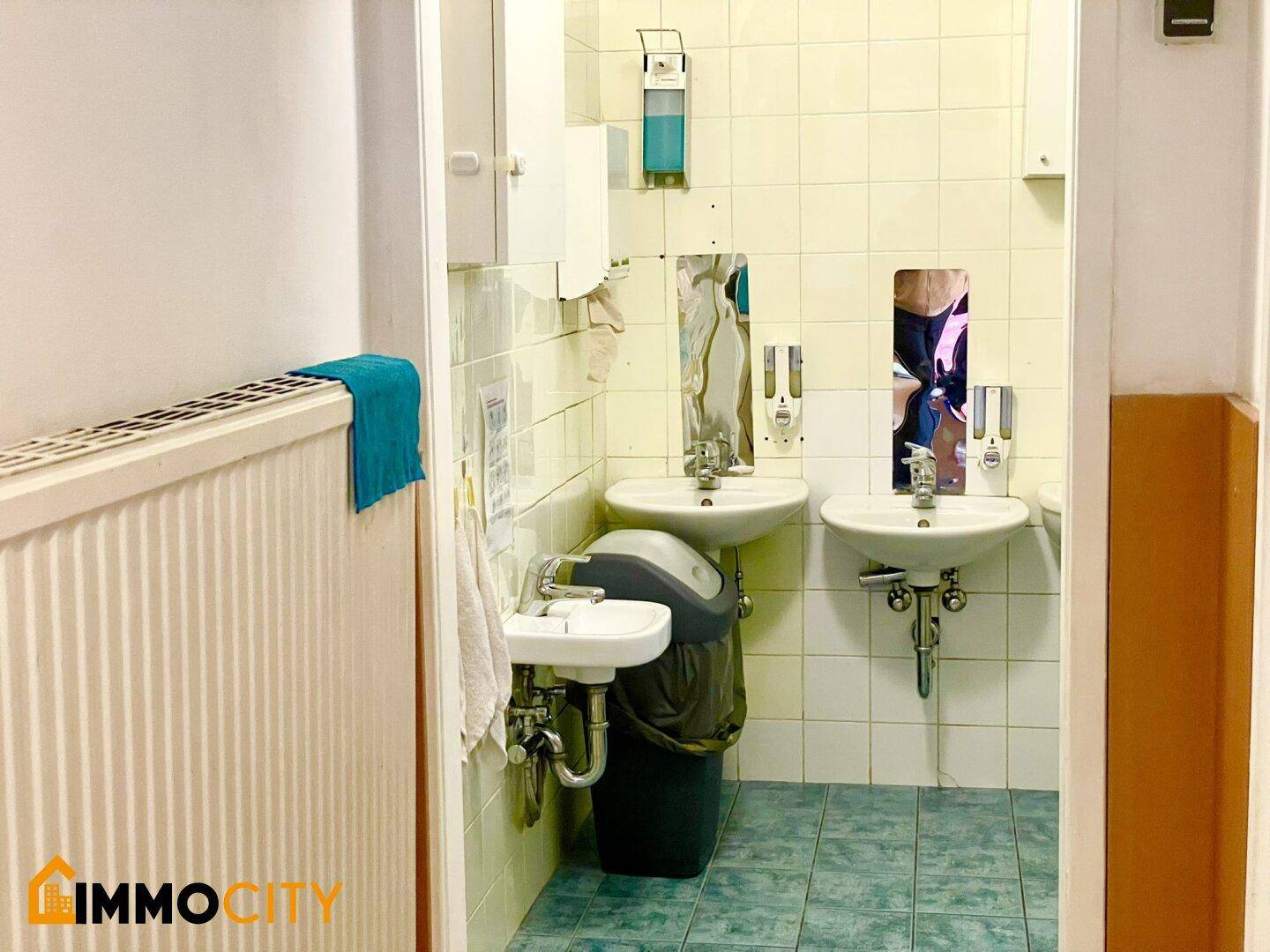 Kinderbadezimmer mit mehreren kleinen Waschbecken und Spiegeln, gefliest in Hellblau und Weiß.