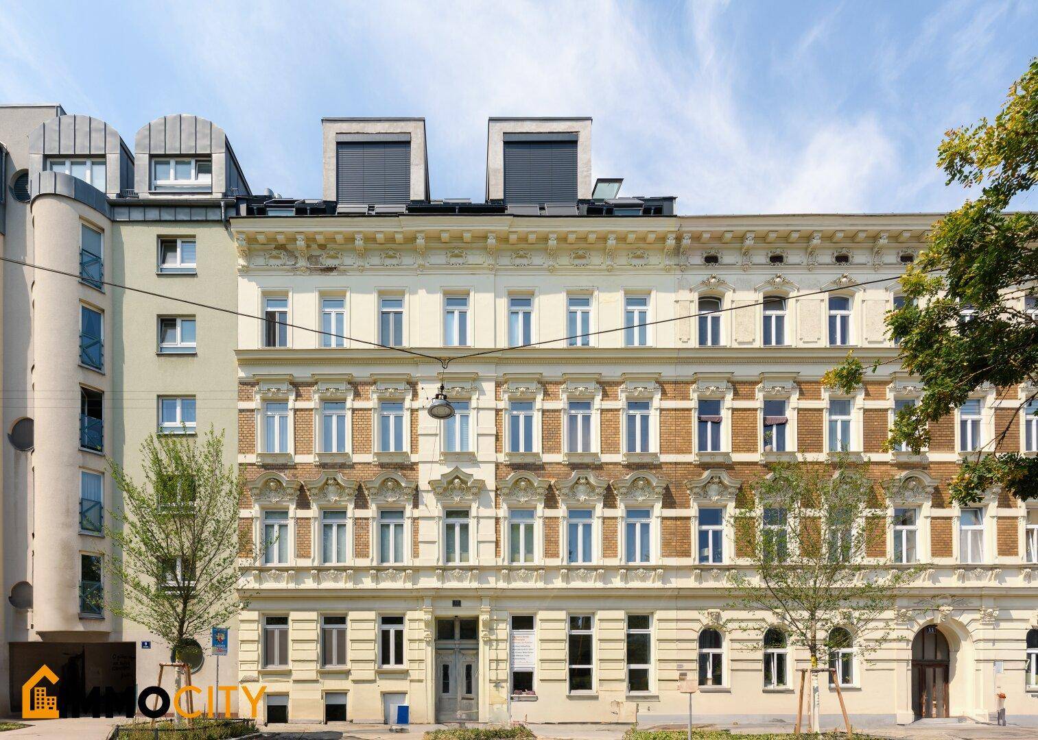 Historische Fassade eines Altbaus mit vielen Fenstern und dekorativen Elementen.