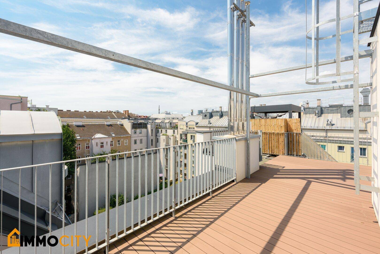 Geräumige Dachterrasse mit Holzboden und weitem Blick über die Dächer der Stadt.